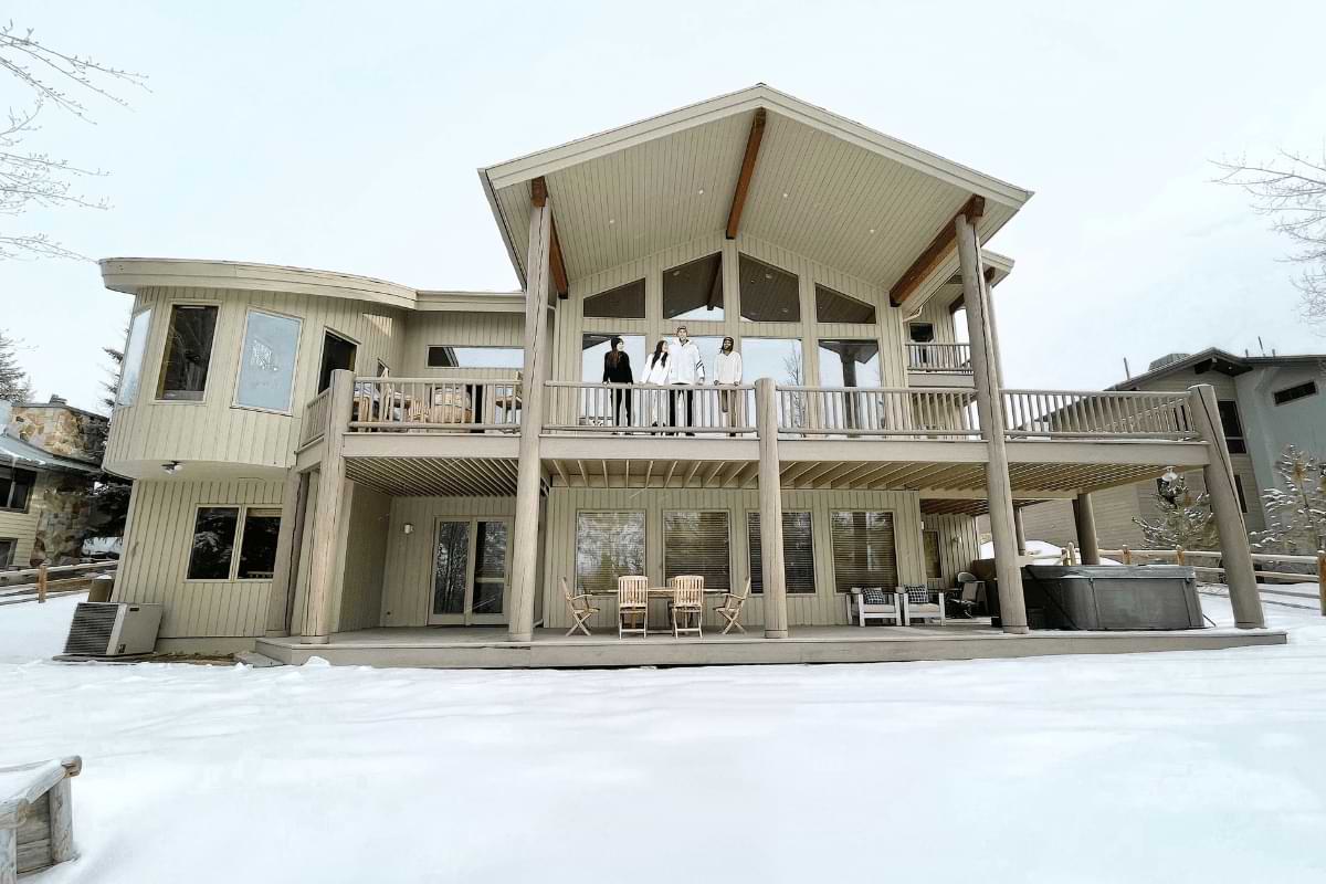 The back of a large AvantStay home covered in snow