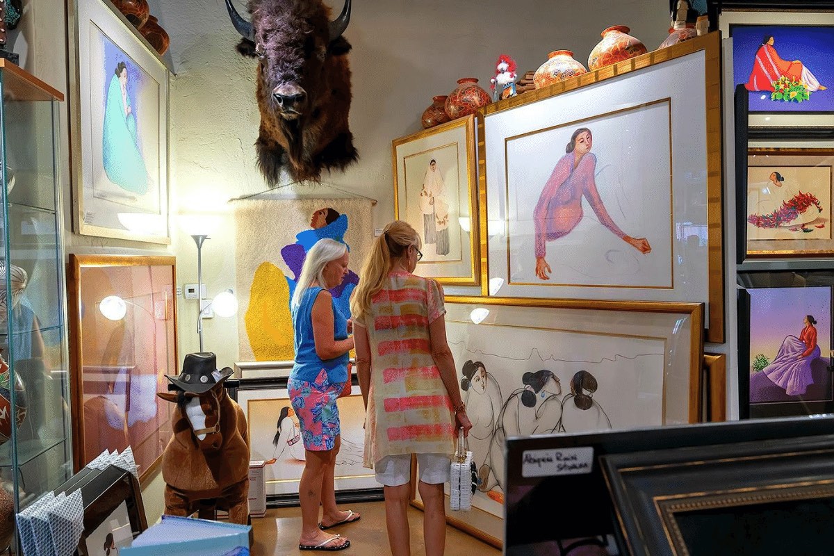 Two women look at paintings and other artwork within a gallery at Scottsdale's ArtWalk