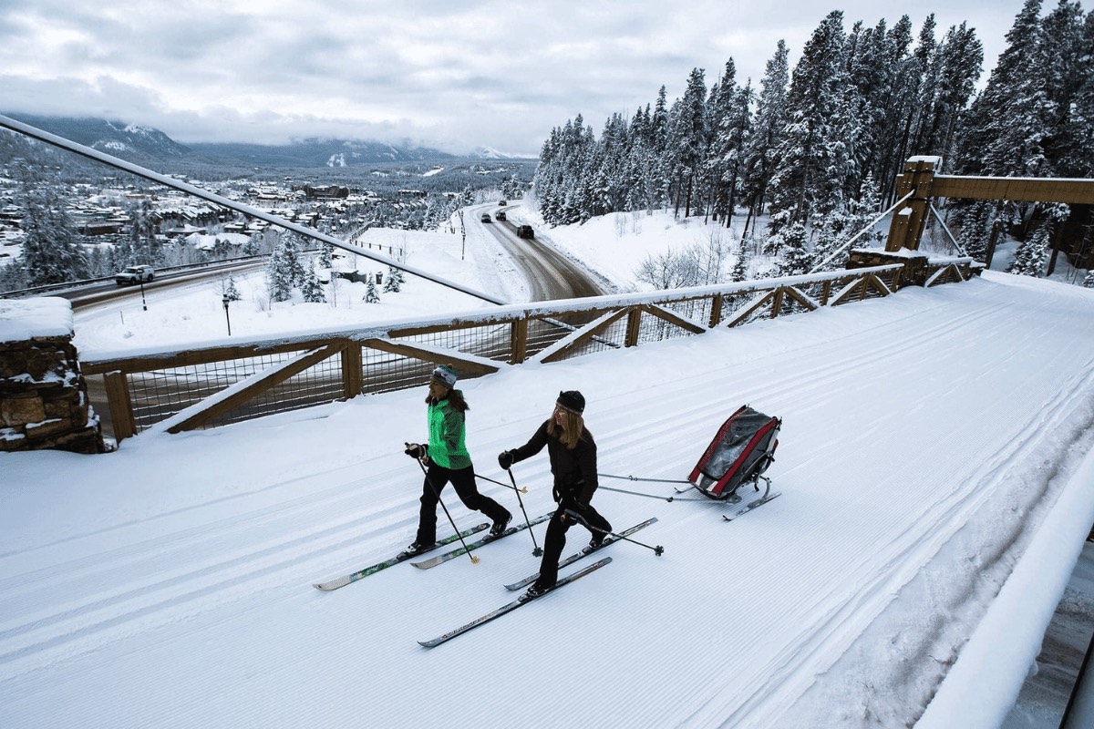 Two people cross-country skiing across a snowy bridge in Breckenridge
