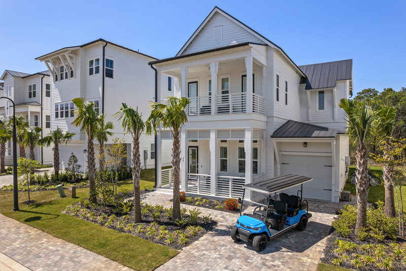 big white mansion by the beach with blue golf cart and 3 palm trees at airbnb 30a