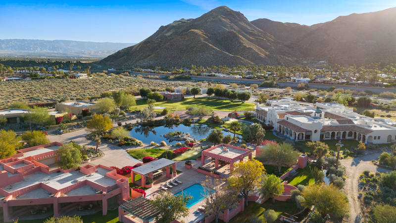 big compound of 3 pink houses that can sleep 20 with a pond in between and mountains as the backdrop in the middle of a desert