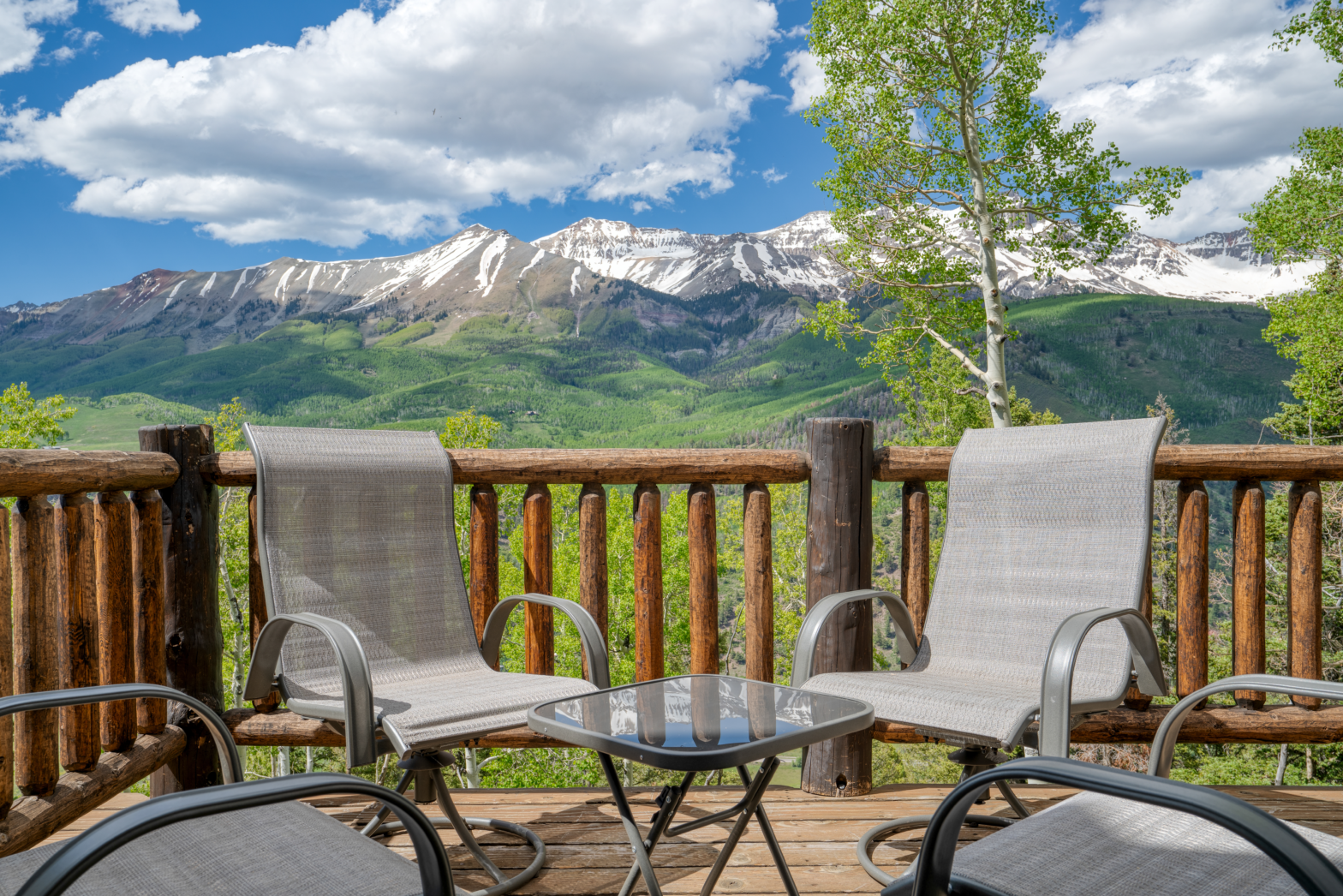 2 rattan chairs placed on wooden deck overlooking the Switzerland like mountain snow capped